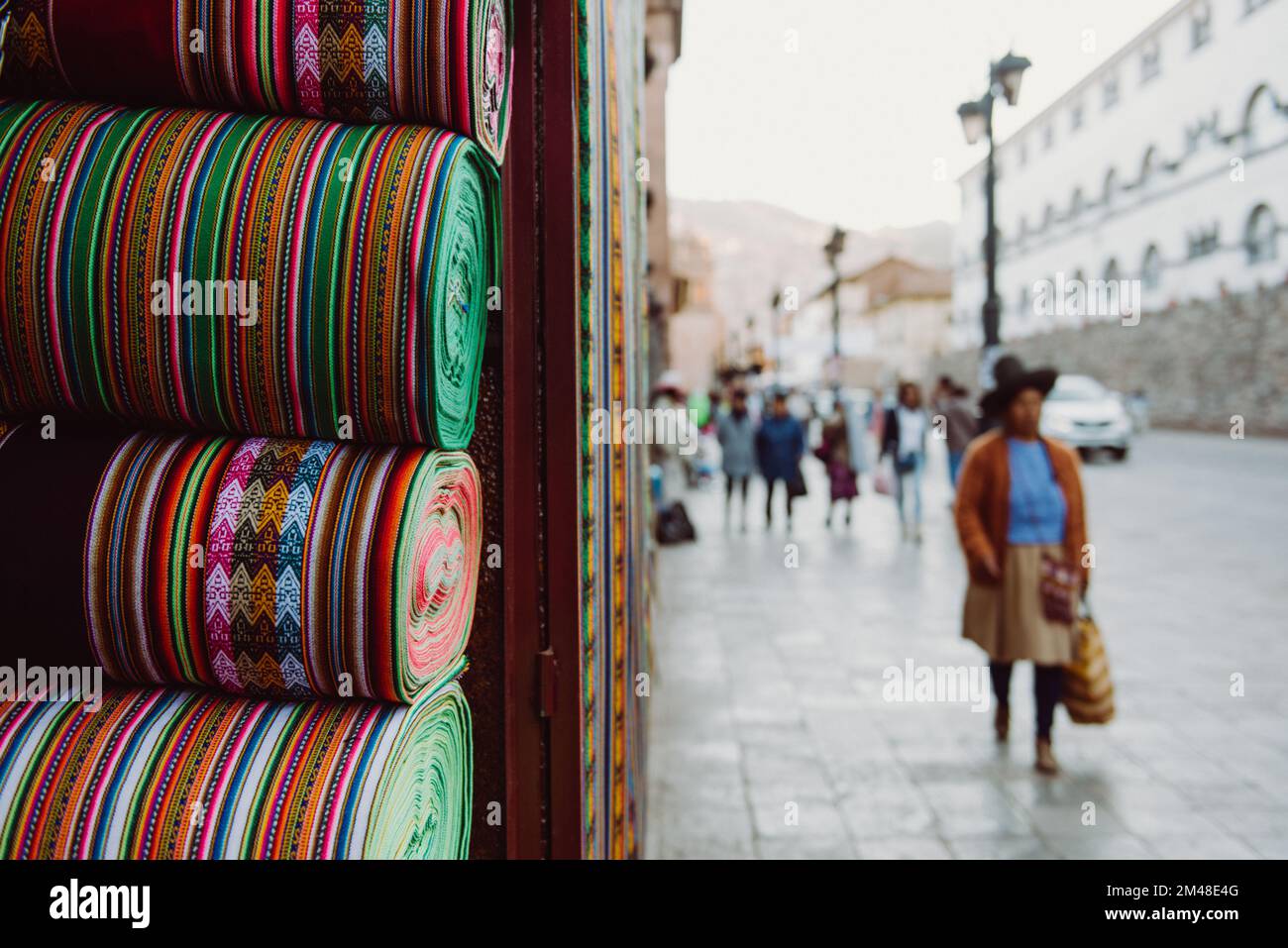 Tessuti peruviani e boliviani tradizionali in perù cusco. Signora nativa che cammina sullo sfondo Foto Stock
