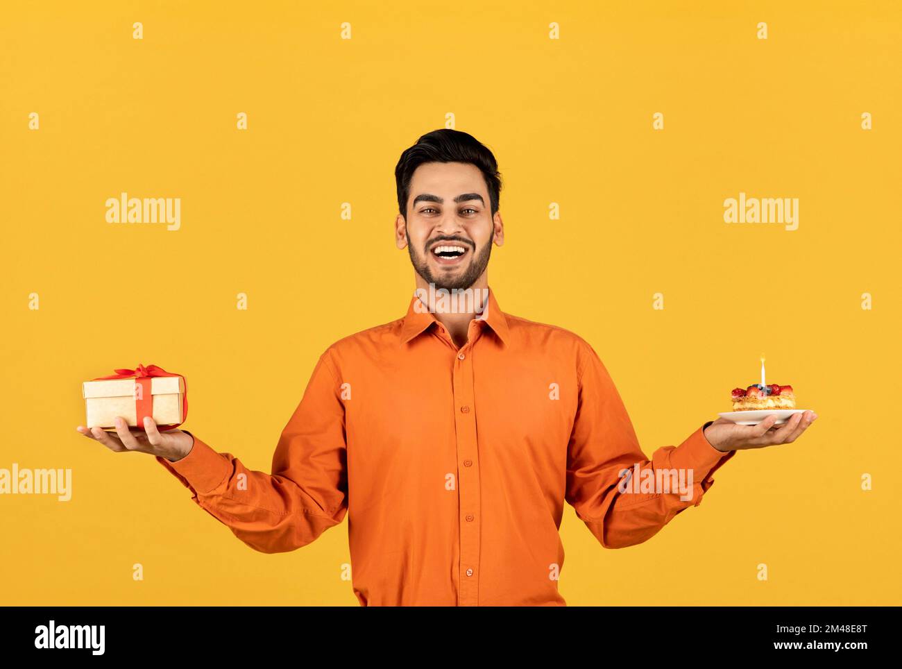 Buon compleanno. Gioioso uomo arabo con confezione regalo e torta con candela Foto Stock