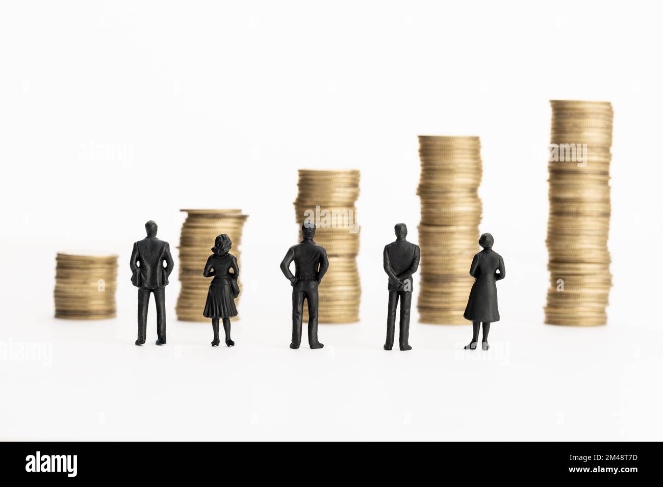 Gruppo di figurine che guardano a pile crescenti di monete. Concetto di crescita aziendale o finanziaria. Spazio di copia Foto Stock