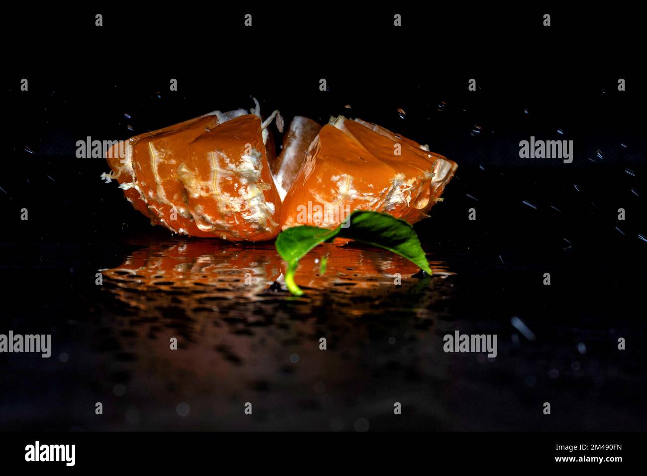 Tagliare il tangerino con spruzzi d'acqua su sfondo nero Foto Stock