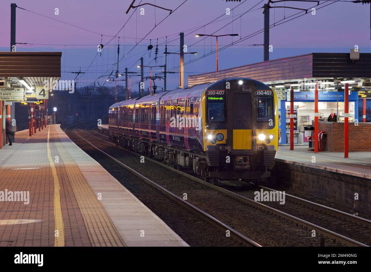 Primo treno elettrico Transpennine Express classe 350 350407calling alla stazione di Wigan North Western sulla linea principale della costa occidentale all'alba Foto Stock