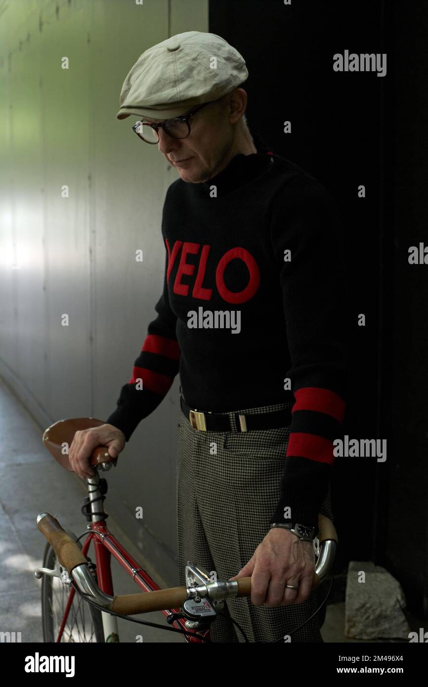 Uomo elegante che tiene in mano una bicicletta indossando un ponticello con il logo del velo Foto Stock