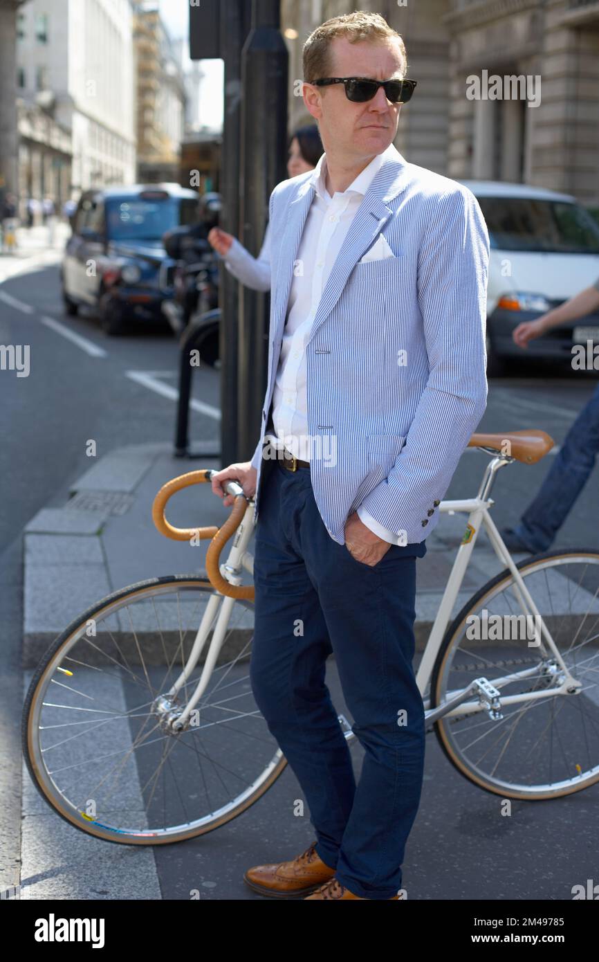 Uomo medio adulto che tiene una bicicletta in città all'aperto Foto Stock