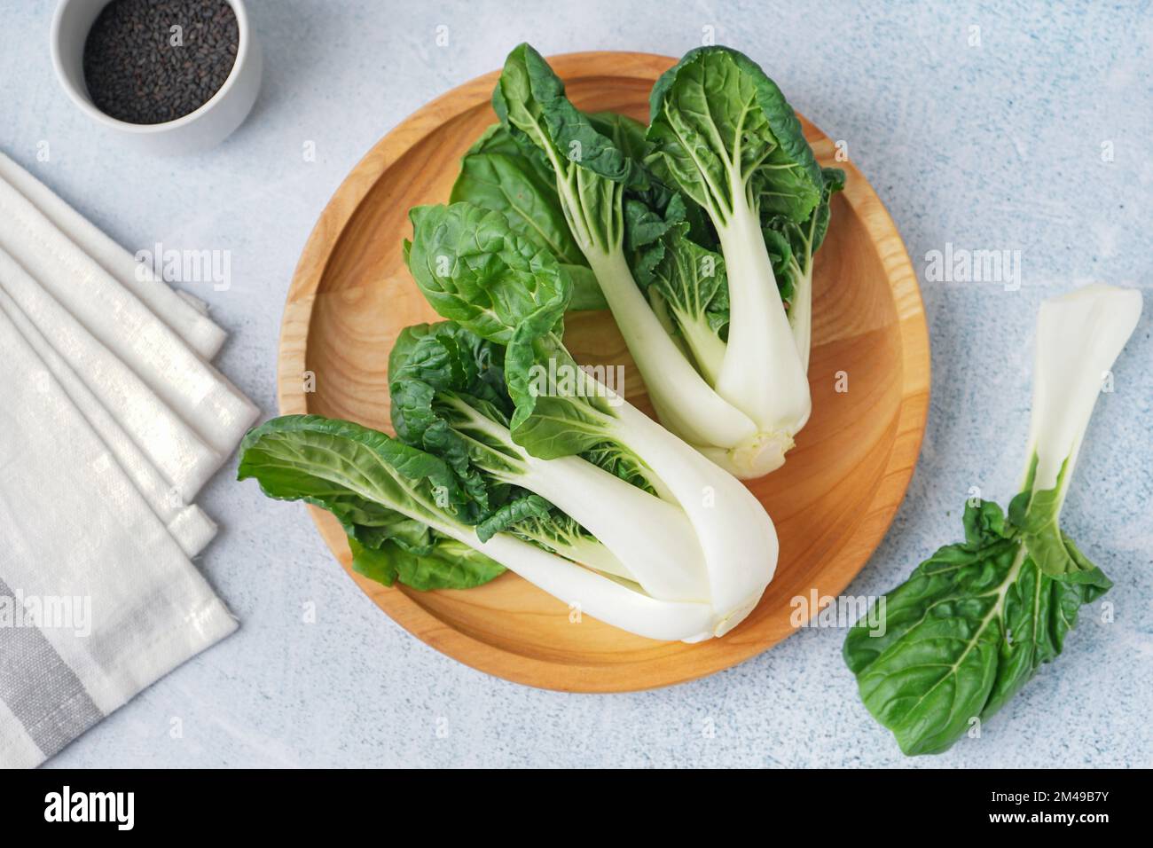 Piatto in legno con cavolo pak choi fresco su fondo chiaro Foto Stock