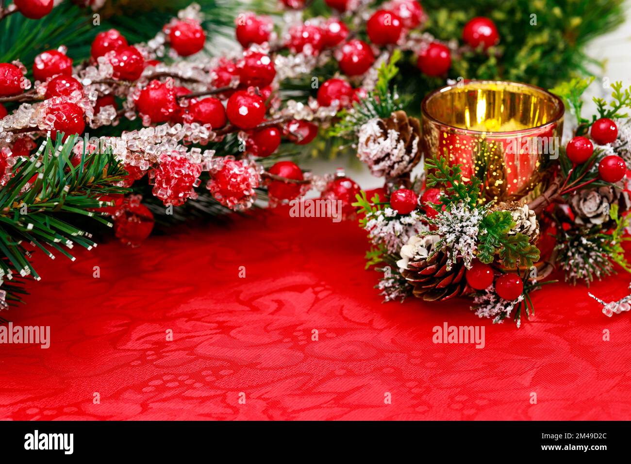 Sfondo di Natale con candela bruciante e bacche rosse. Foto Stock