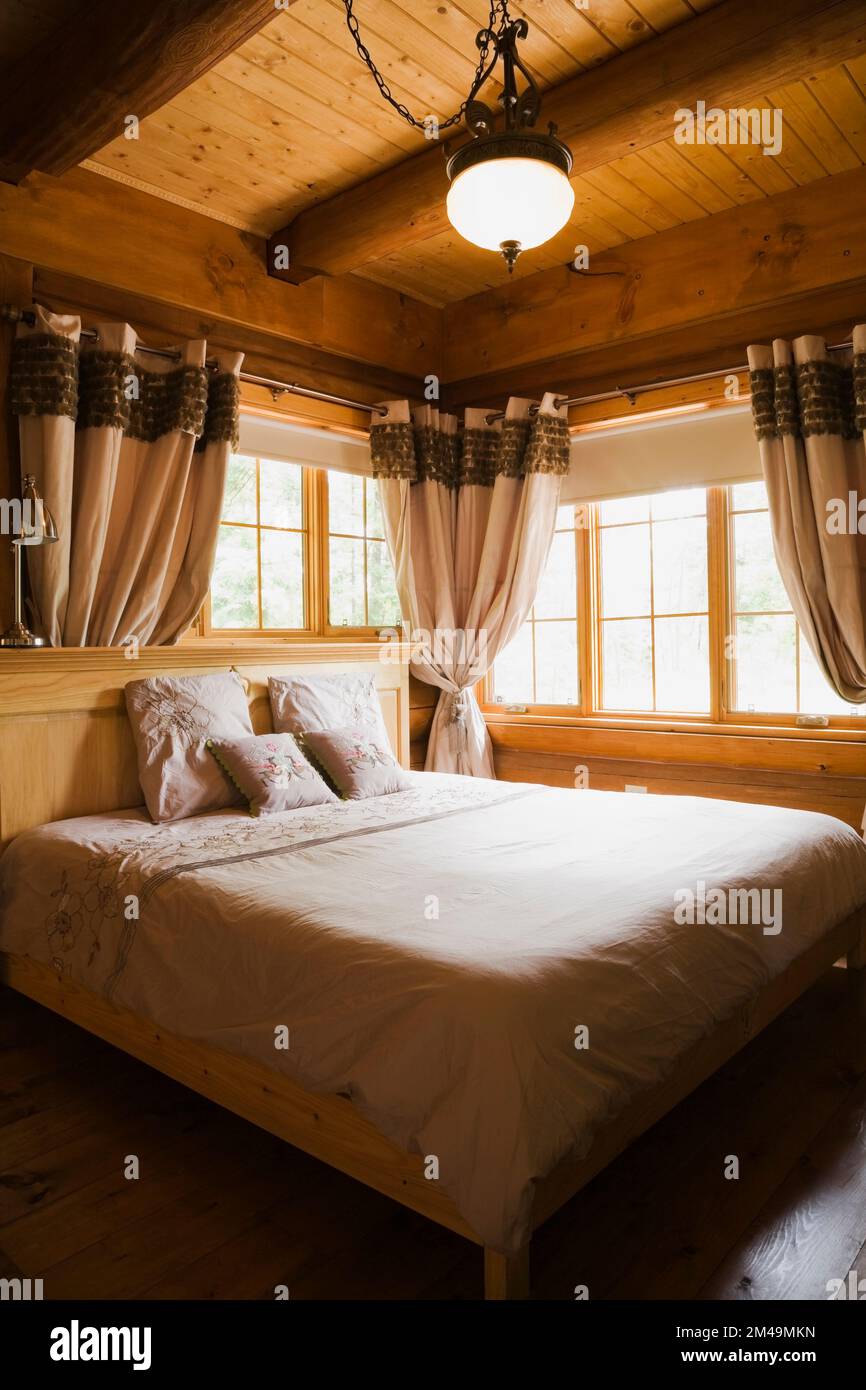 Letto matrimoniale con struttura in legno e testiera in legno nella camera da letto principale all'interno della casa in legno. Foto Stock