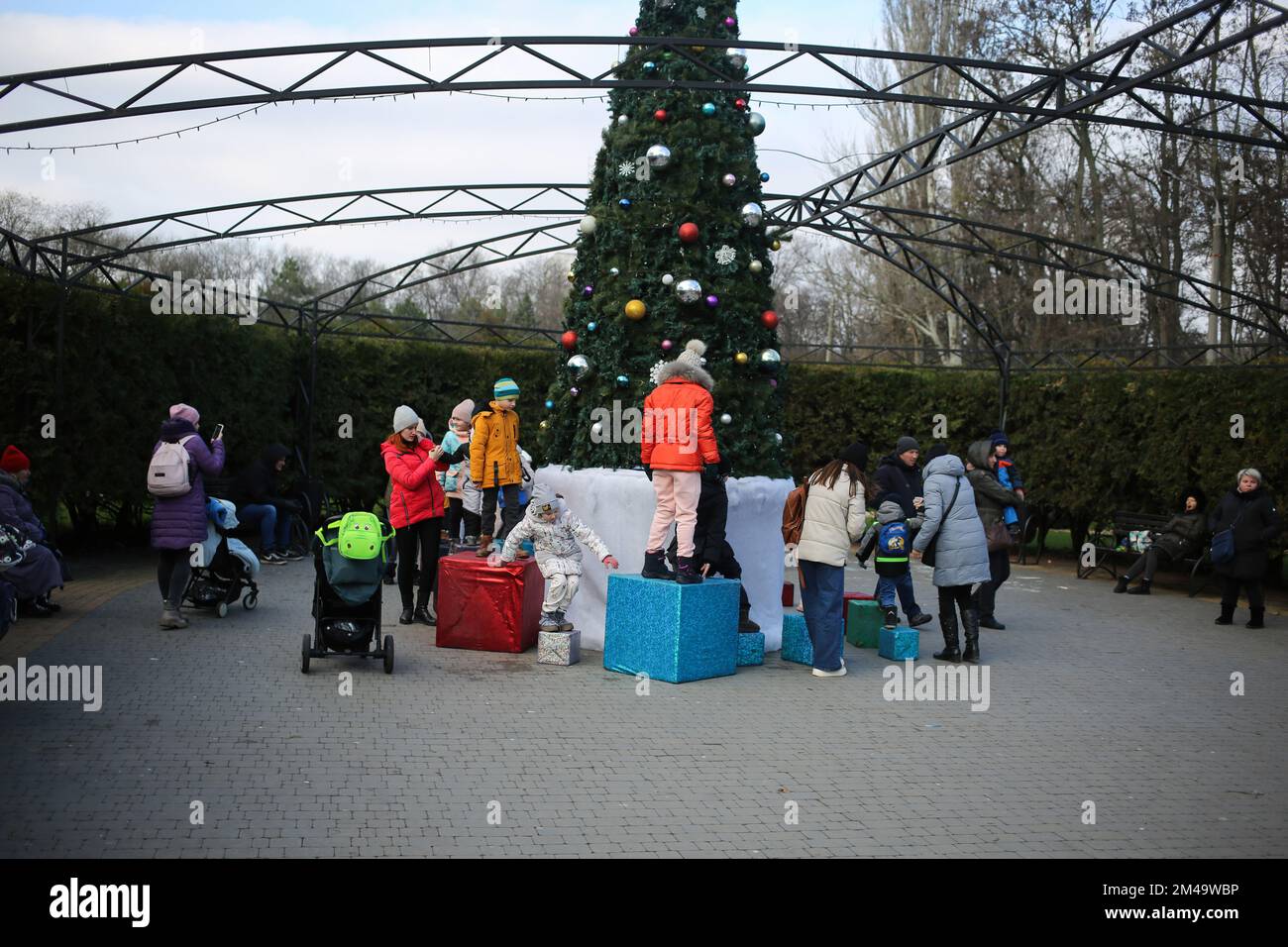 Odessa, Ucraina, 19/12/2022, i bambini sono visti vicino all'albero di Natale come un certo gioco sulle scatole del regalo. La residenza di St. Nicholas aprì nel parco che prende il nome da Maxim Gorky. Il 19 dicembre, i cristiani celebrano una grande festa - San Giorno di Nicholas. Nicola il Wonderworker - un santo nelle chiese storiche, arcivescovo del mondo di Lycia (Bisanzio). Nel cristianesimo è venerato come operaio di miracoli, in Oriente è patrono di viaggiatori, prigionieri e orfani, in Occidente è patrono di quasi tutti i settori della società, ma soprattutto dei bambini. Foto Stock