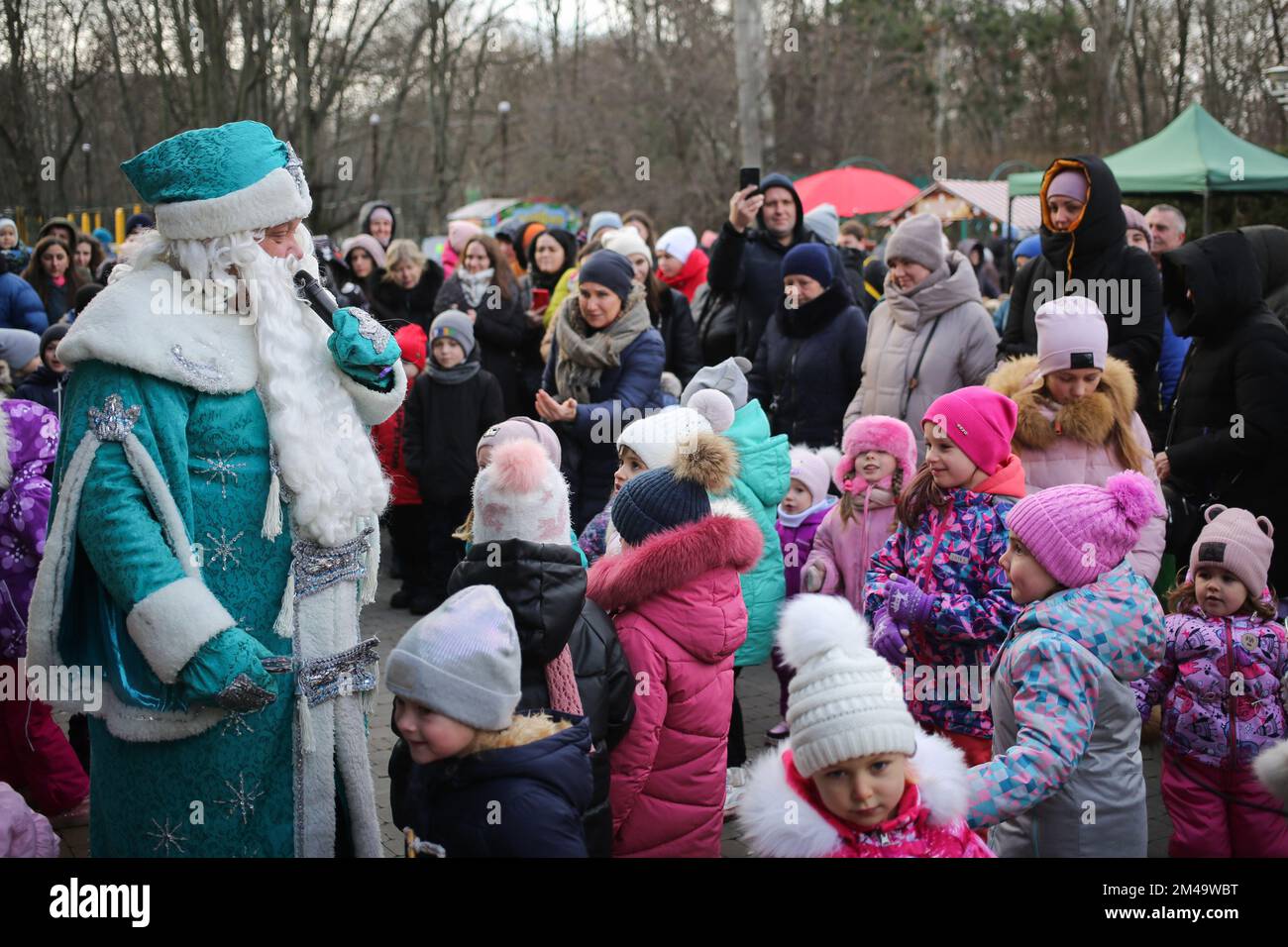 Odessa, Ucraina, 19/12/2022, un animatore vestito come St. Nicholas interagisce con i bambini di St. Giorno di Nicholas. La residenza di St. Nicholas aprì nel parco che prende il nome da Maxim Gorky. Il 19 dicembre, i cristiani celebrano una grande festa - San Giorno di Nicholas. Nicola il Wonderworker - un santo nelle chiese storiche, arcivescovo del mondo di Lycia (Bisanzio). Nel cristianesimo è venerato come operaio di miracoli, in Oriente è patrono di viaggiatori, prigionieri e orfani, in Occidente è patrono di quasi tutti i settori della società, ma soprattutto dei bambini. Foto Stock