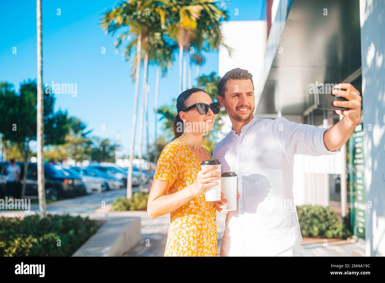 Giovane coppia con caffè per andare in strada nella città estiva prendendo selfie Foto Stock