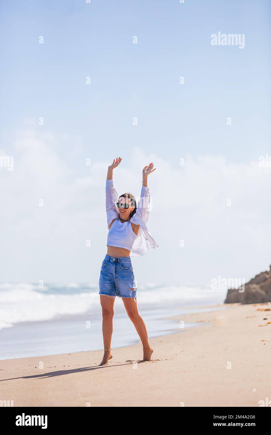 Giovane donna felice sulla spiaggia godere del vento Foto Stock