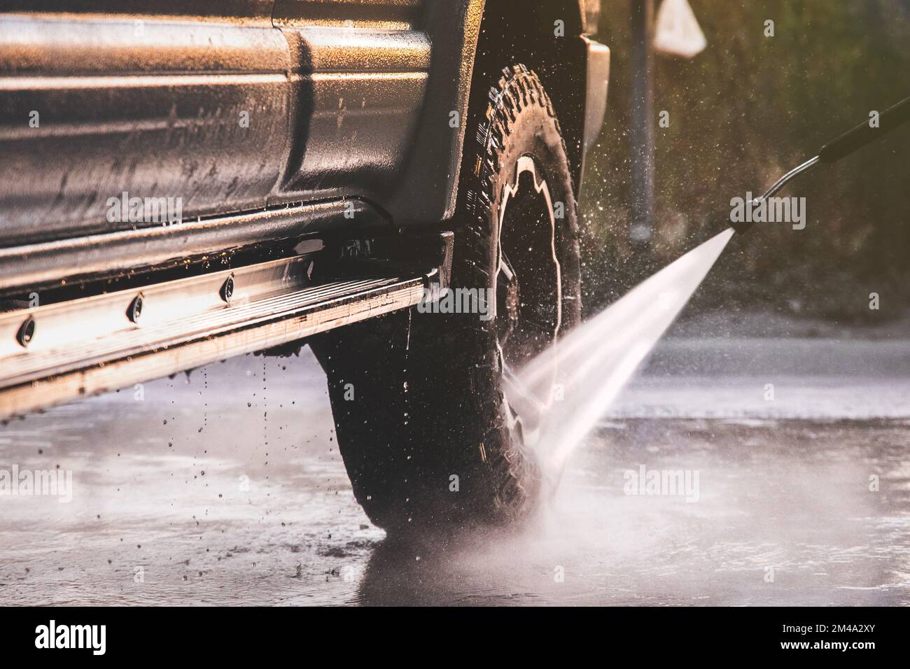 Lavaggio di un'auto offroader in un autolavaggio self-service con getto d'acqua ad alta pressione dopo la guida fuoristrada Foto Stock