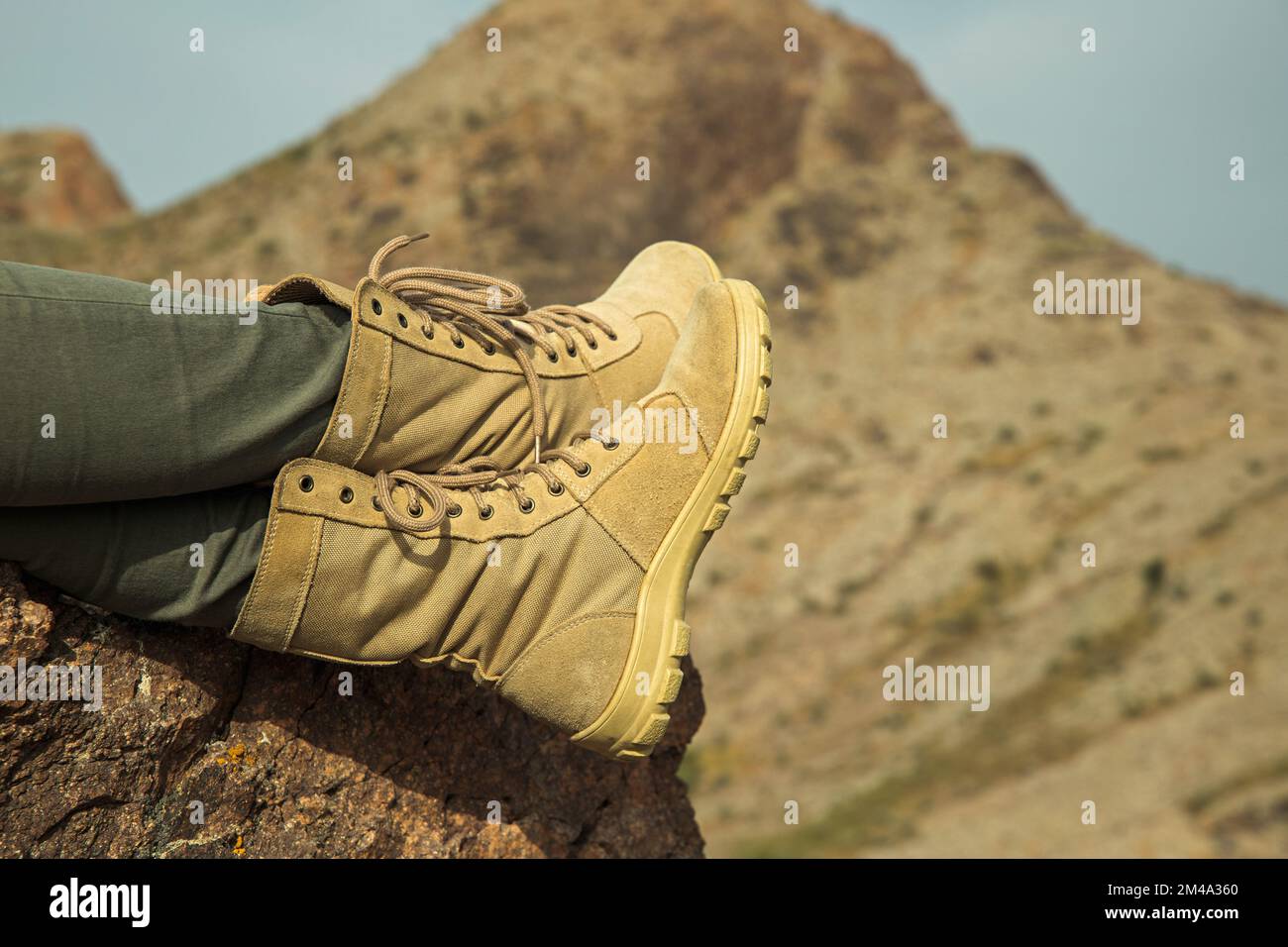 Primo piano delle gambe femminili dei viaggiatori con scarponi da trekking che si rilassano sulla roccia durante il trekking Foto Stock