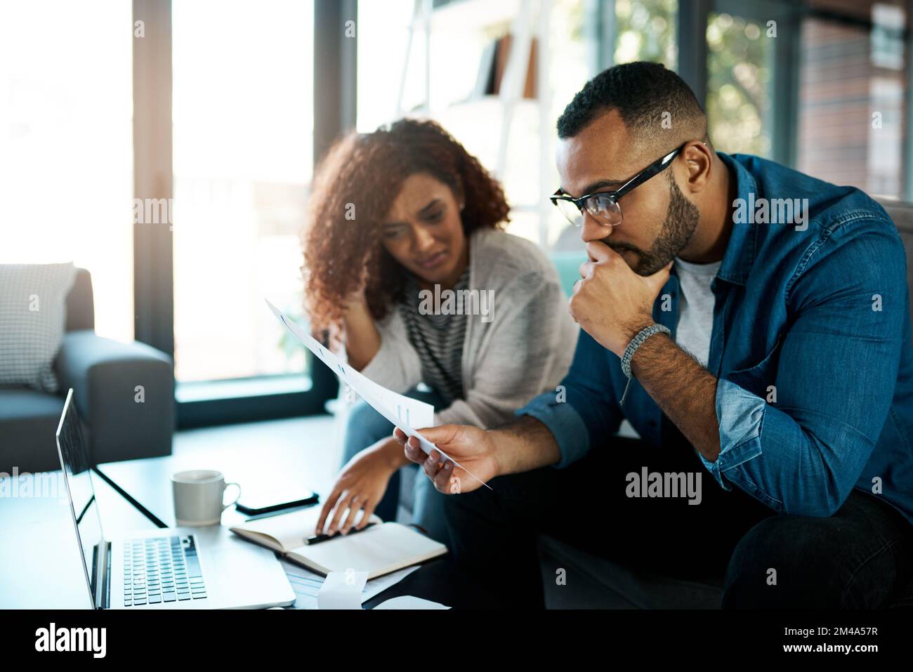 Theyre preoccupato per lo stato delle loro spese. una giovane coppia che guarda ha sottolineato mentre lavorando al loro bilancio a casa. Foto Stock