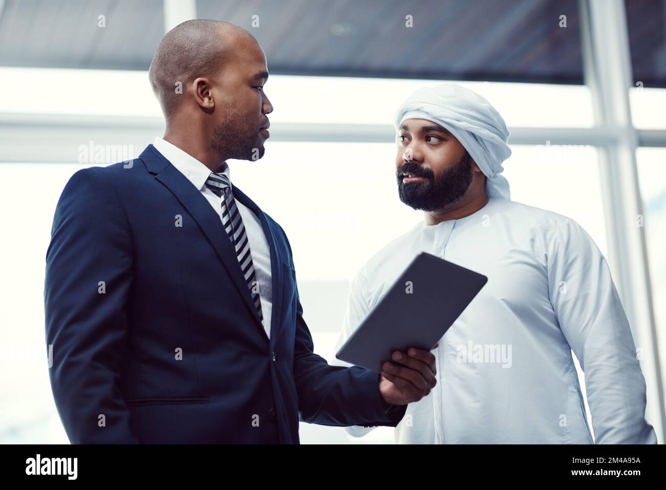 Dirigersi su un impero con acumen esperto di affari. due uomini d'affari che utilizzano un tablet digitale mentre discutano in un ufficio moderno. Foto Stock