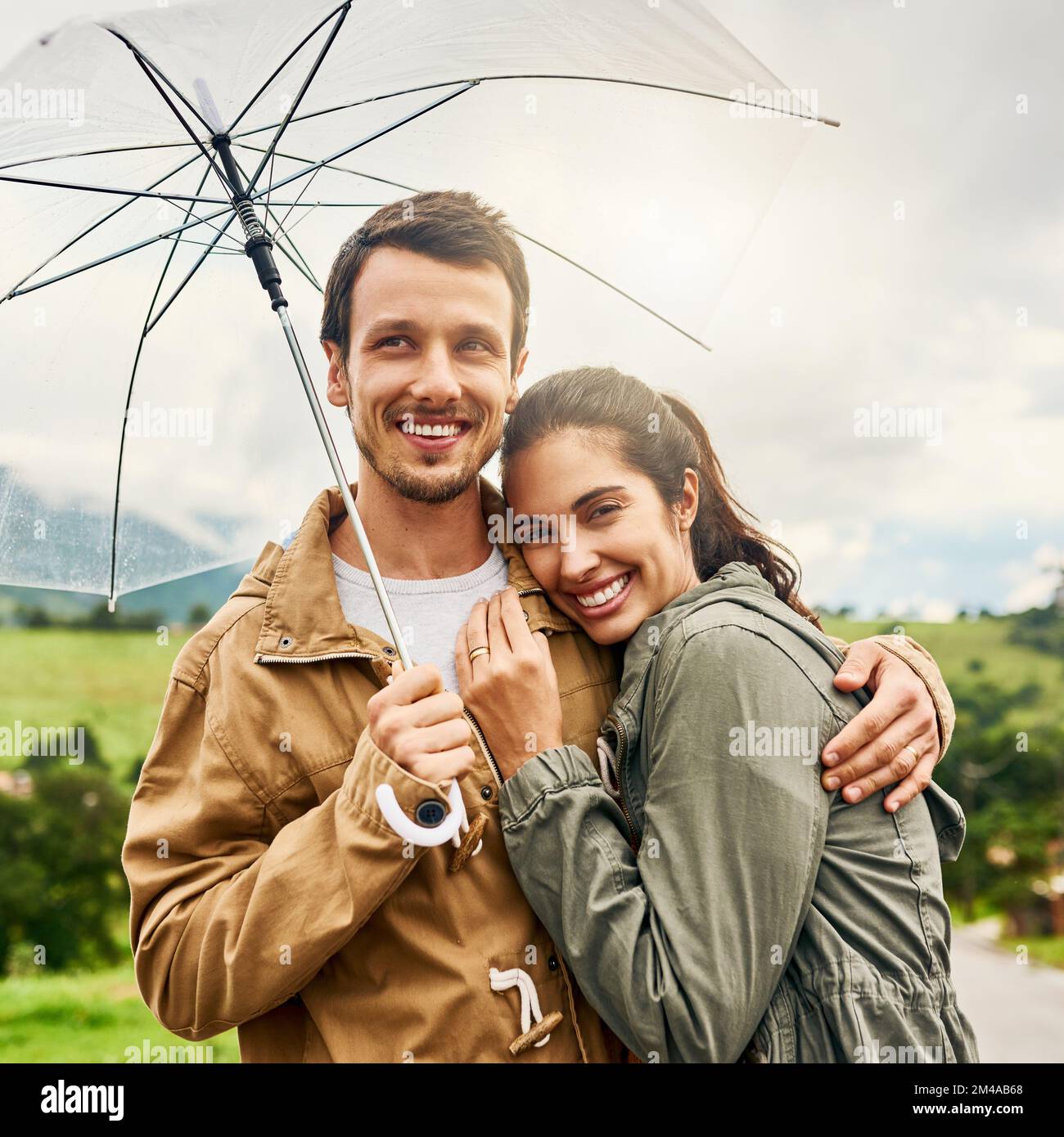 Il matrimonio consiste nel superare qualsiasi condizione climatica. una coppia amorevole in piedi fuori con un ombrello. Foto Stock