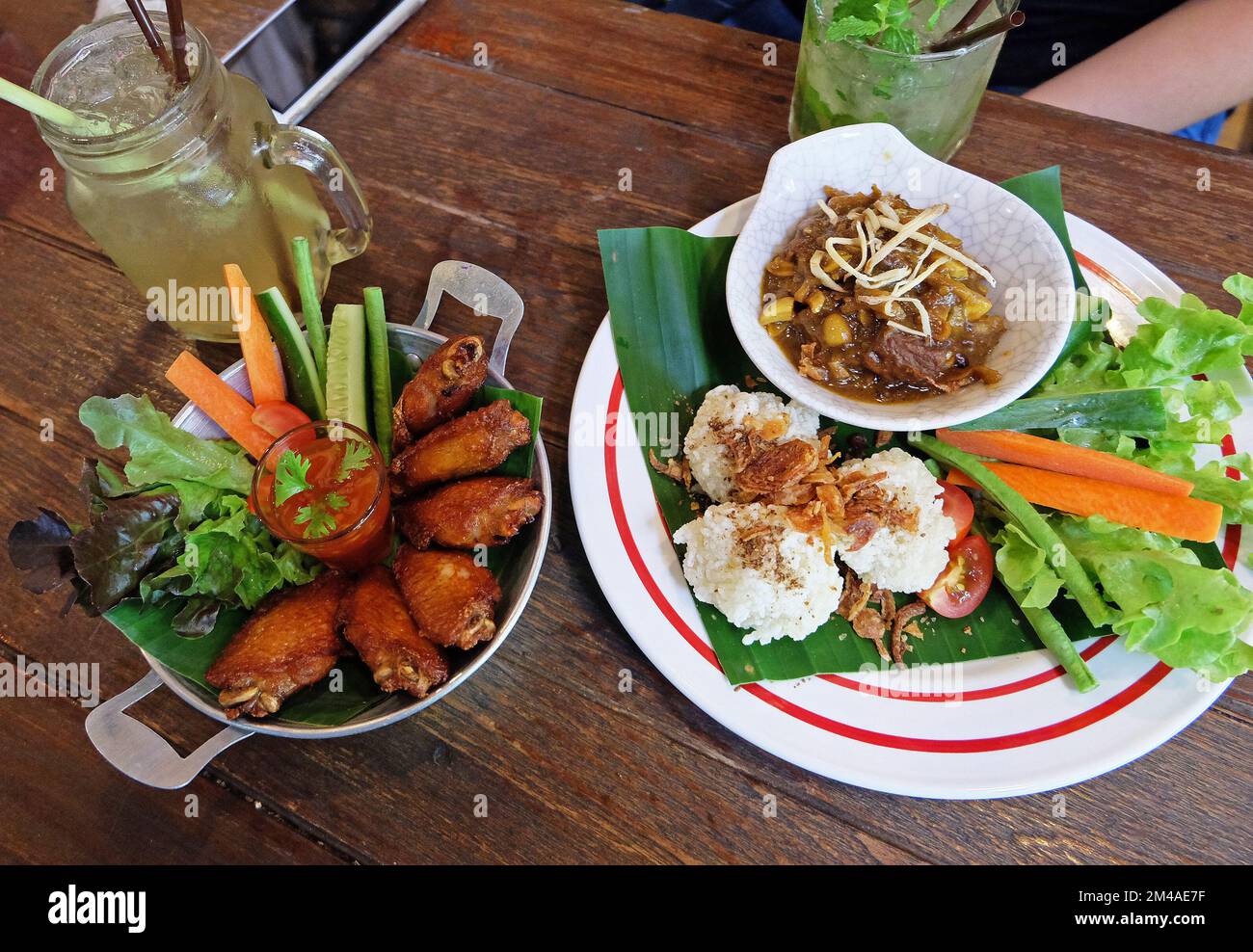 Riso appiccicoso fritto servito con curry della Thailandia settentrionale, ali di pollo e calamari fritti in pastella Foto Stock