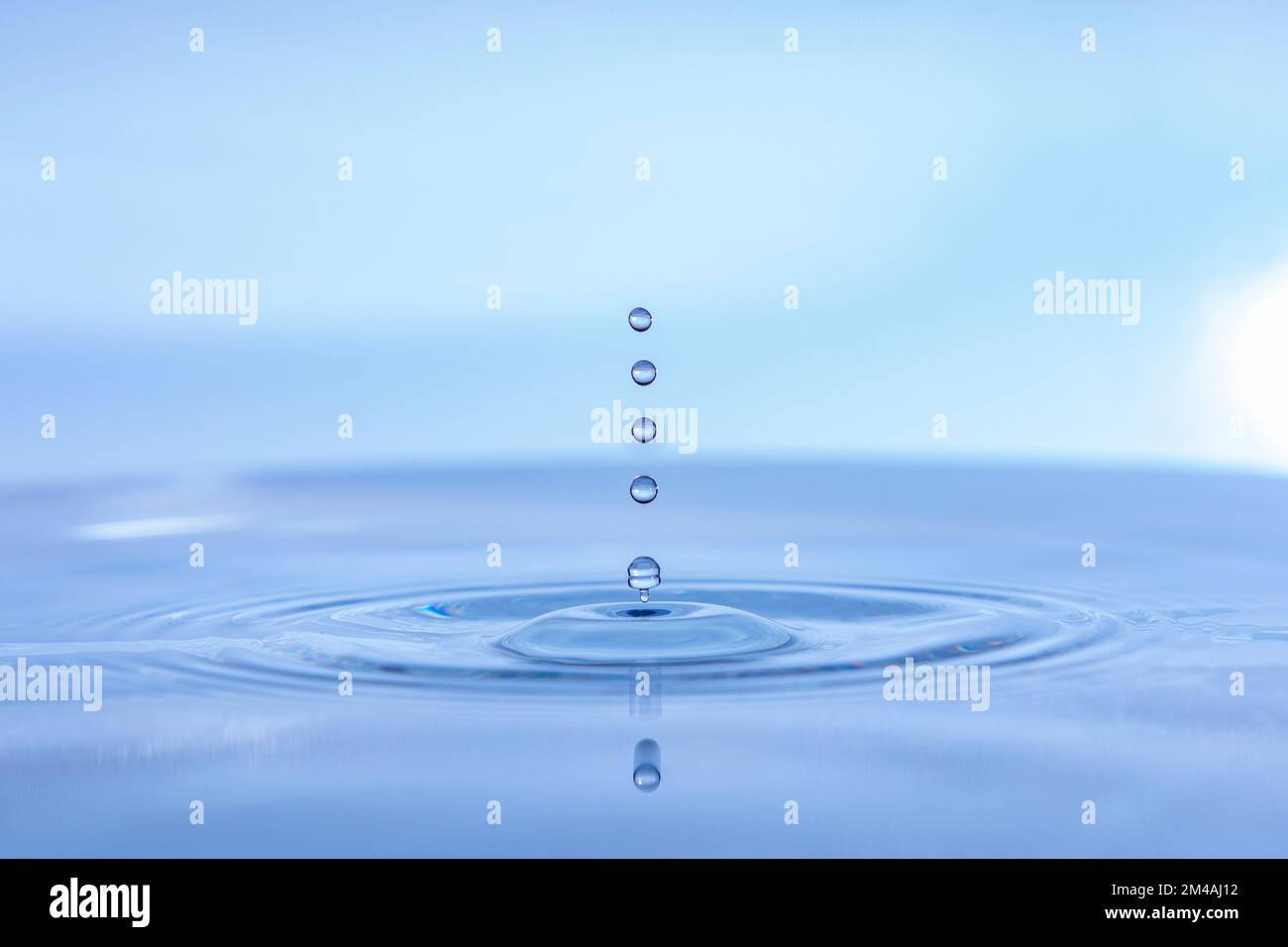 Gocce d'acqua che cadono sull'acqua, sfondo blu, onde d'acqua Foto Stock