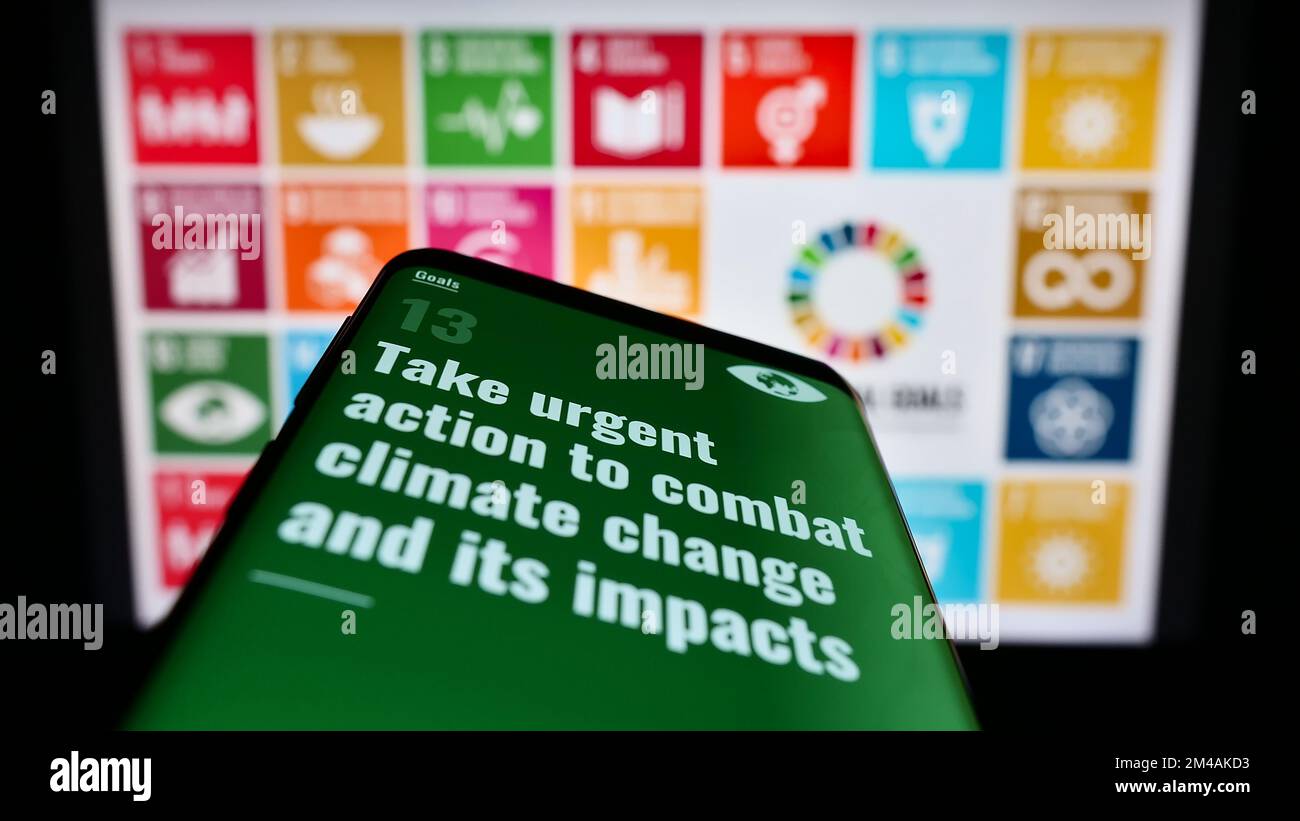 Telefono cellulare con pagina web degli obiettivi di sviluppo sostenibile delle Nazioni Unite (SDG) sullo schermo davanti al logo. Messa a fuoco in alto a sinistra del display del telefono. Foto Stock