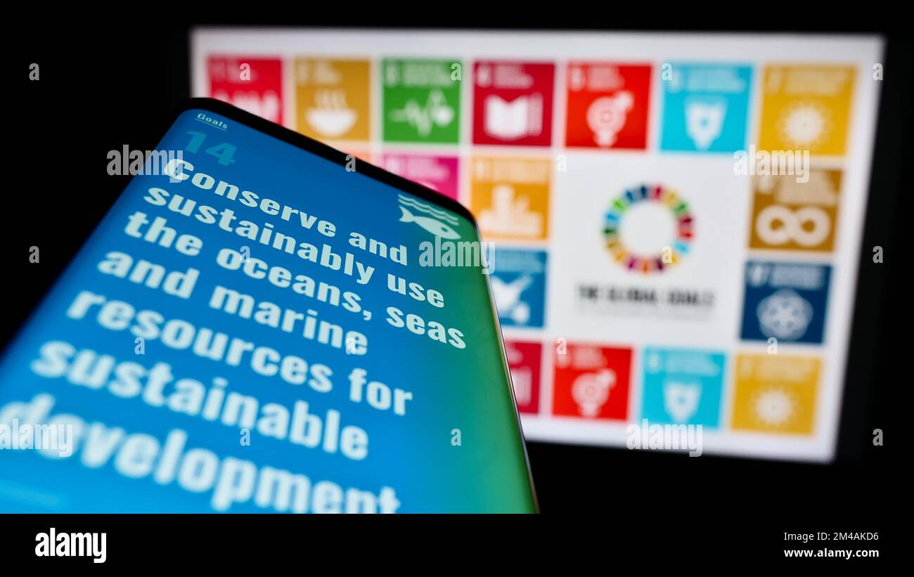 Smartphone con pagina Web degli obiettivi di sviluppo sostenibile delle Nazioni Unite (SDG) sullo schermo davanti al logo. Messa a fuoco in alto a sinistra del display del telefono. Foto Stock