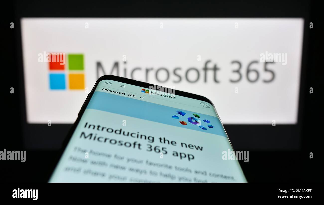 Telefono cellulare con sito Web del software di produttività Microsoft 365 sullo schermo di fronte al logo aziendale. Messa a fuoco in alto a sinistra del display del telefono. Foto Stock