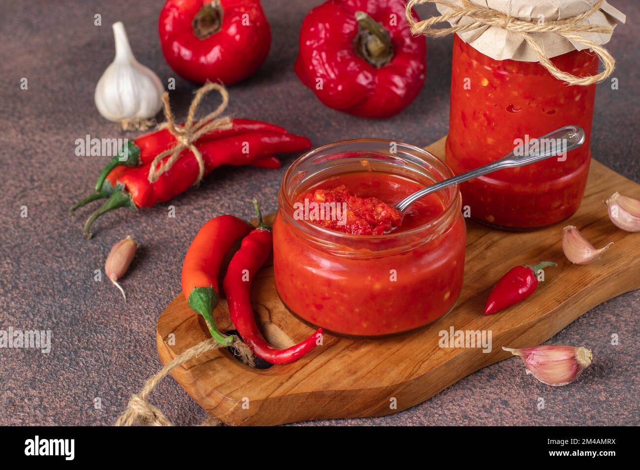 Salsa tradizionale con peperoncino piccante, pasta harissa in vaso di vetro su tavolo marrone Foto Stock