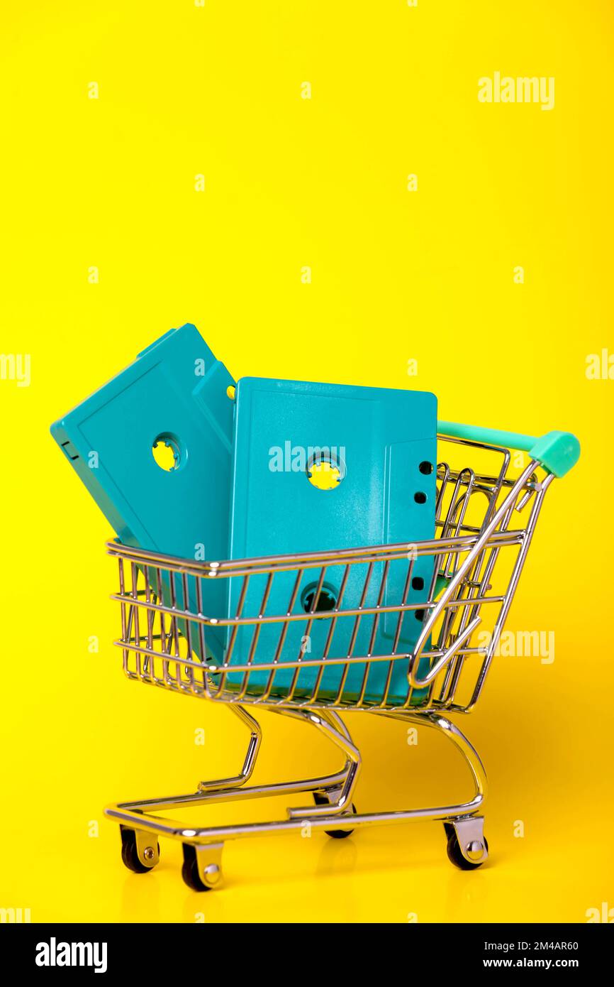 Le audiocassette blu retro sono collocate nel carrello in metallo su sfondo giallo Foto Stock