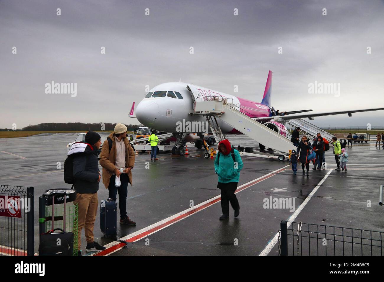 BEAUVAIS, FRANCIA - 11 DICEMBRE 2019: I passeggeri sbarcano dall'Airbus A320 sotto la pioggia della compagnia aerea a basso costo Wizzair all'aeroporto di Beauvais, Francia. Imbarco b Foto Stock