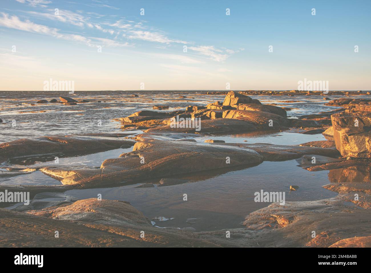 Bella alba sulla riva del Mar Bianco con pietre e alghe al sole mattina Belomorsk, Carelia. Immagine tinta. Foto Stock
