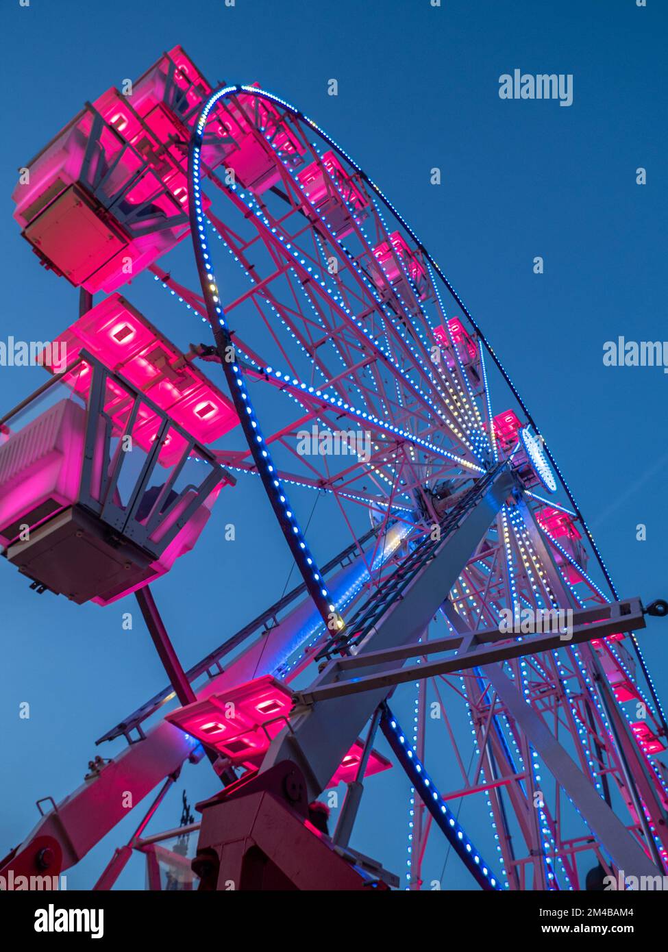 ruota panoramica illuminata rosa su un cielo blu Foto Stock