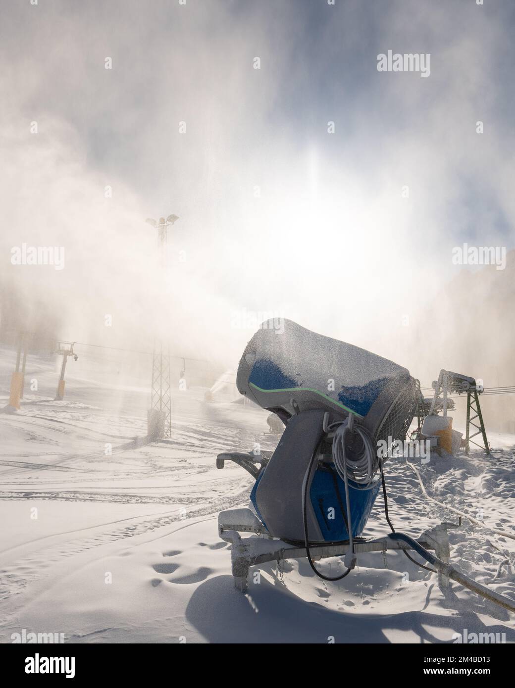 Macchina per innevamento cannone da neve o pistola in azione in una fredda giornata invernale di sole nella località sciistica di Kranjska Gora, Slovenia Foto Stock
