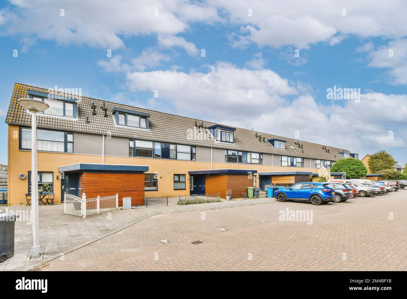 un complesso di appartamenti con auto parcheggiate nel vialetto e due edifici su entrambi i lati, un edificio è in mattoni rossi Foto Stock