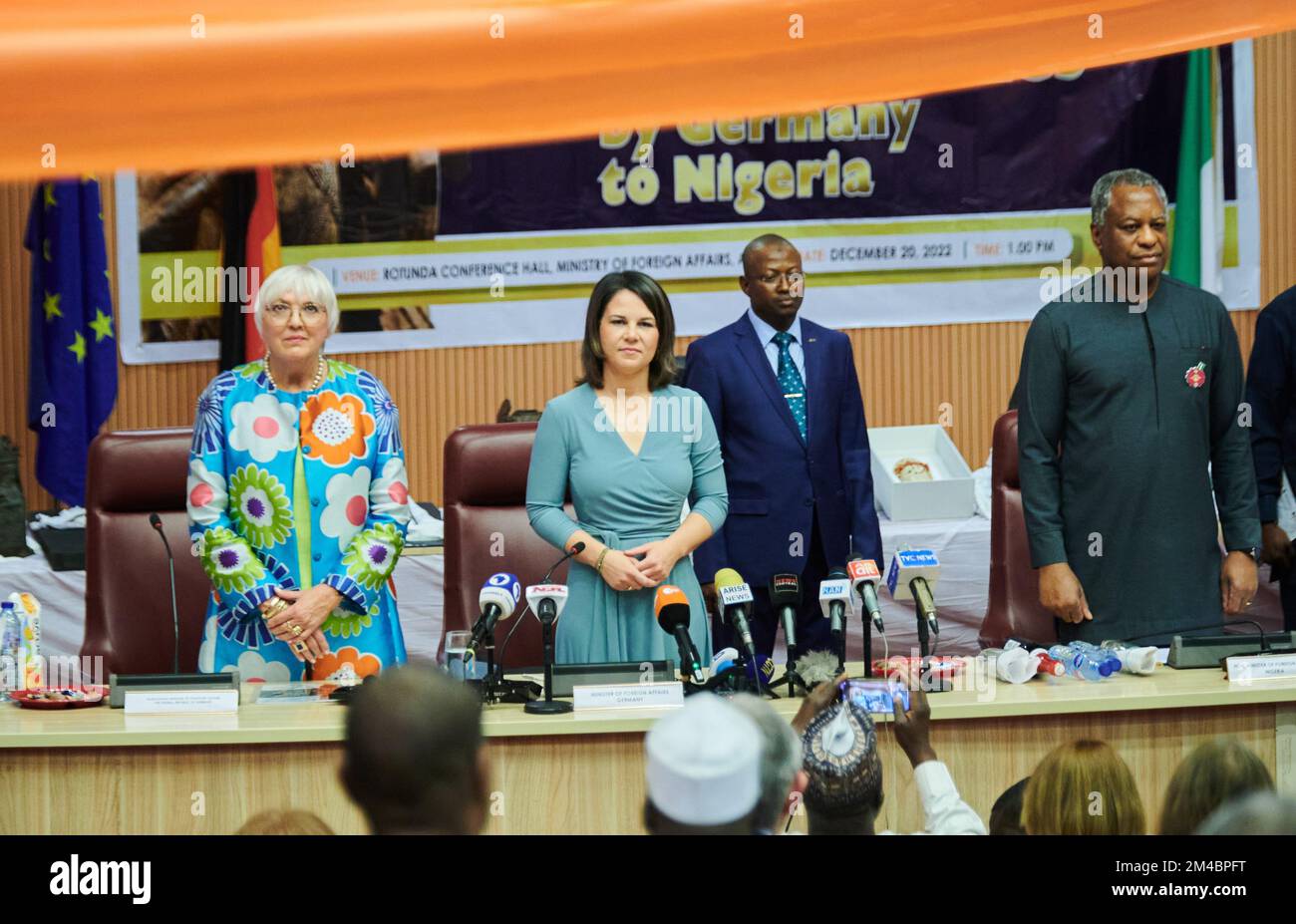 20 dicembre 2022, Nigeria, Abuja: Claudia Roth (l, Bündnis 90/Die Grünen), ministro della Cultura e dei Media, Annalena Baerbock (2nd da sinistra, Bündnis 90/Die Grünen), ministro degli Esteri, e Geoffrey Onyeama (r), ministro degli Esteri nigeriano, stanno in piedi mentre suonano gli inni nazionali di entrambi i paesi. In una mossa che ha attirato l'attenzione internazionale, il ministro degli Esteri Berbock e il ministro della Cultura Roth restituiscono preziosi bronzi Benin alla capitale nigeriana Abuja. I tesori d'arte appartenevano in precedenza a collezioni di musei di Berlino, Amburgo, Colonia, Dresda/Lipsia e St Foto Stock