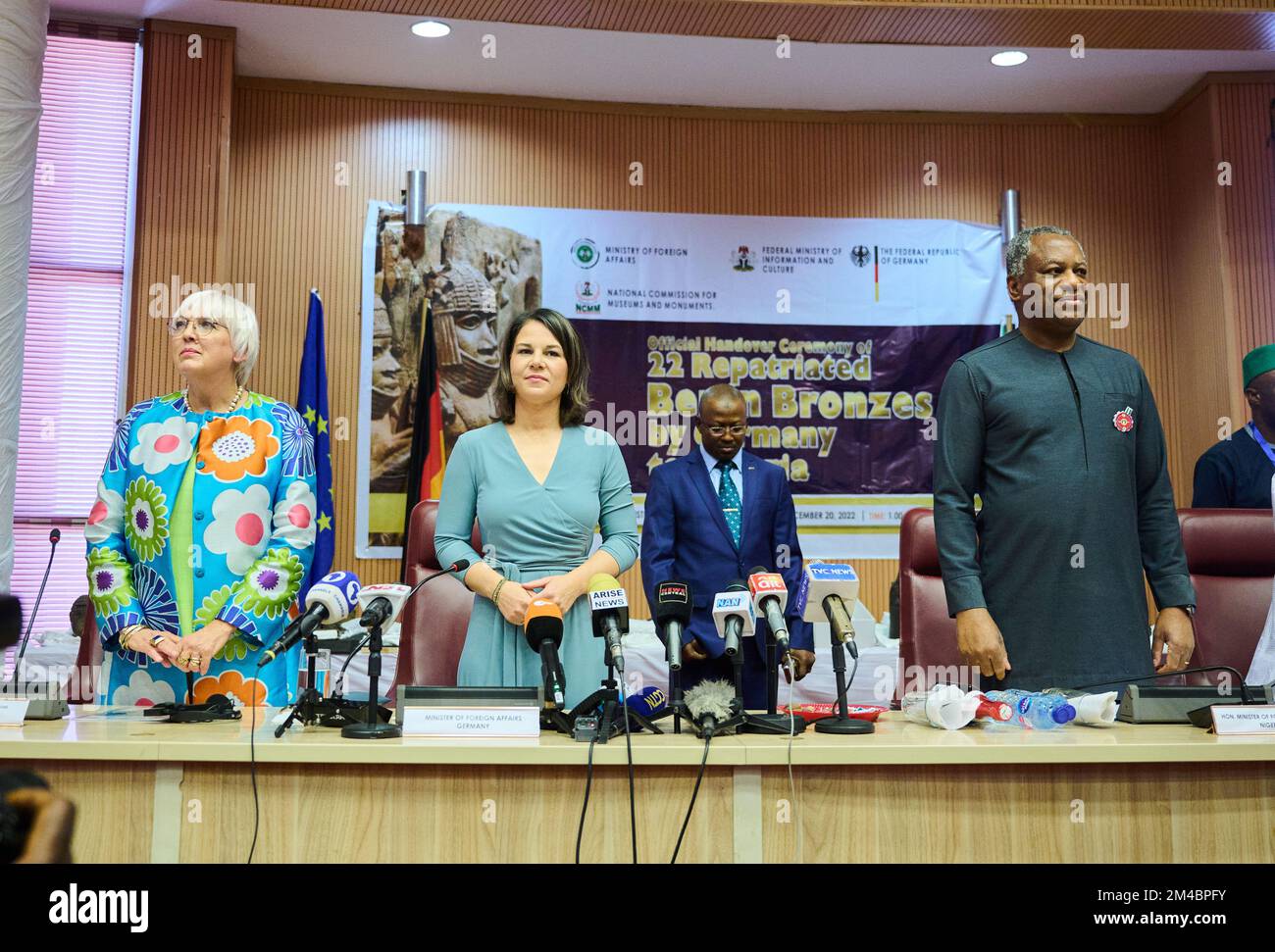 20 dicembre 2022, Nigeria, Abuja: Claudia Roth (l, Bündnis 90/Die Grünen), Ministro della Cultura e dei Media, Annalena Baerbock (2nd da sinistra, Bündnis 90/Die Grünen), Ministro degli Esteri, e Geoffrey Onyeama, Ministro degli Esteri nigeriano, sono presenti al Ministero degli Esteri mentre suonano gli anemi nazionali di entrambi i paesi. In una mossa che attira l'attenzione internazionale, il ministro degli Esteri Berbock e il ministro della Cultura Roth restituiscono preziosi bronzi Benin alla capitale nigeriana Abuja. I tesori d'arte appartenevano in precedenza a collezioni di musei di Berlino, Amburgo, Colonia, Dresda Foto Stock