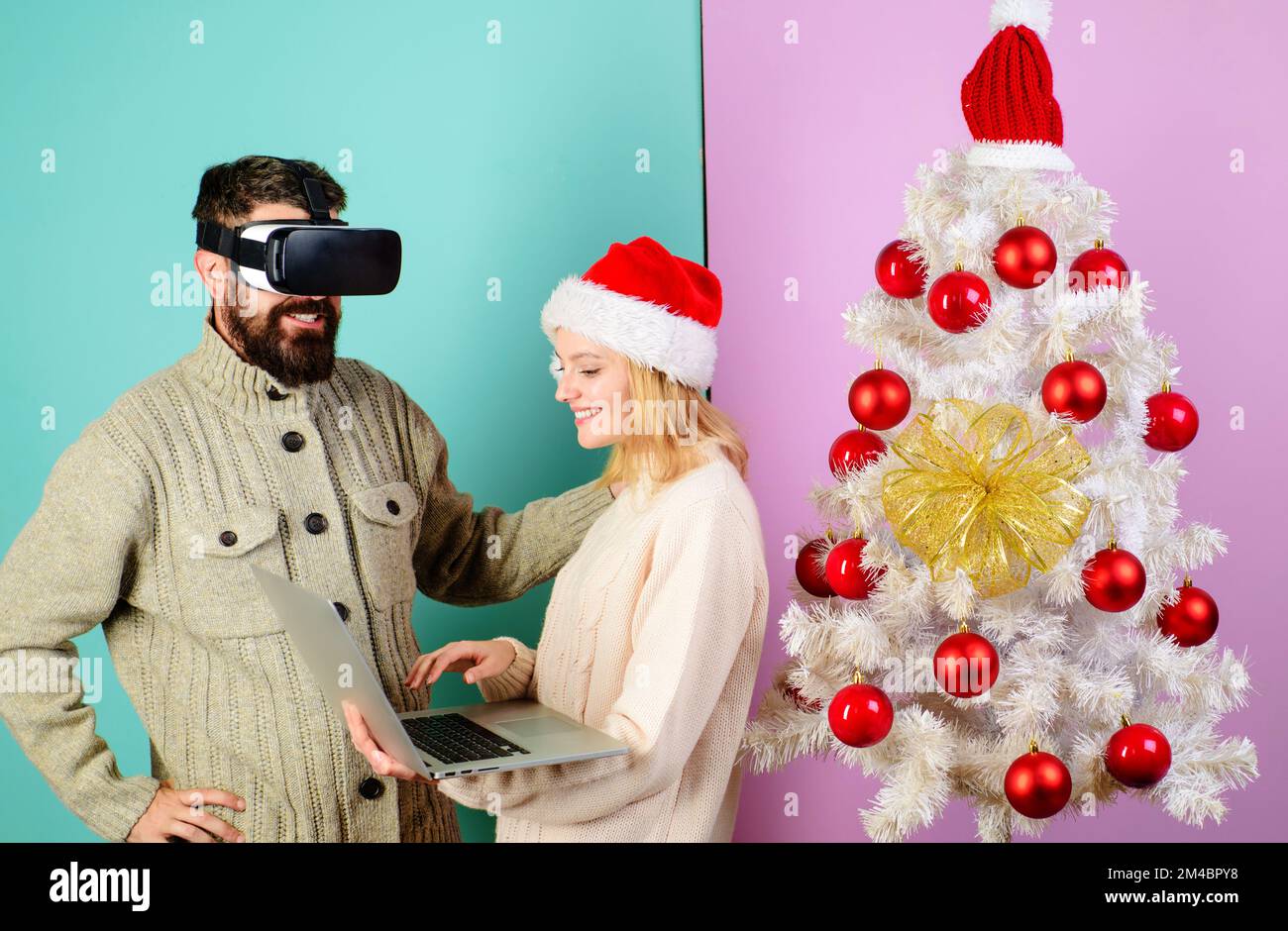 Donna in berretto santa con notebook. Uomo barbuto in occhiali virtuali 3D. tecnologia 3d, realtà virtuale. Foto Stock