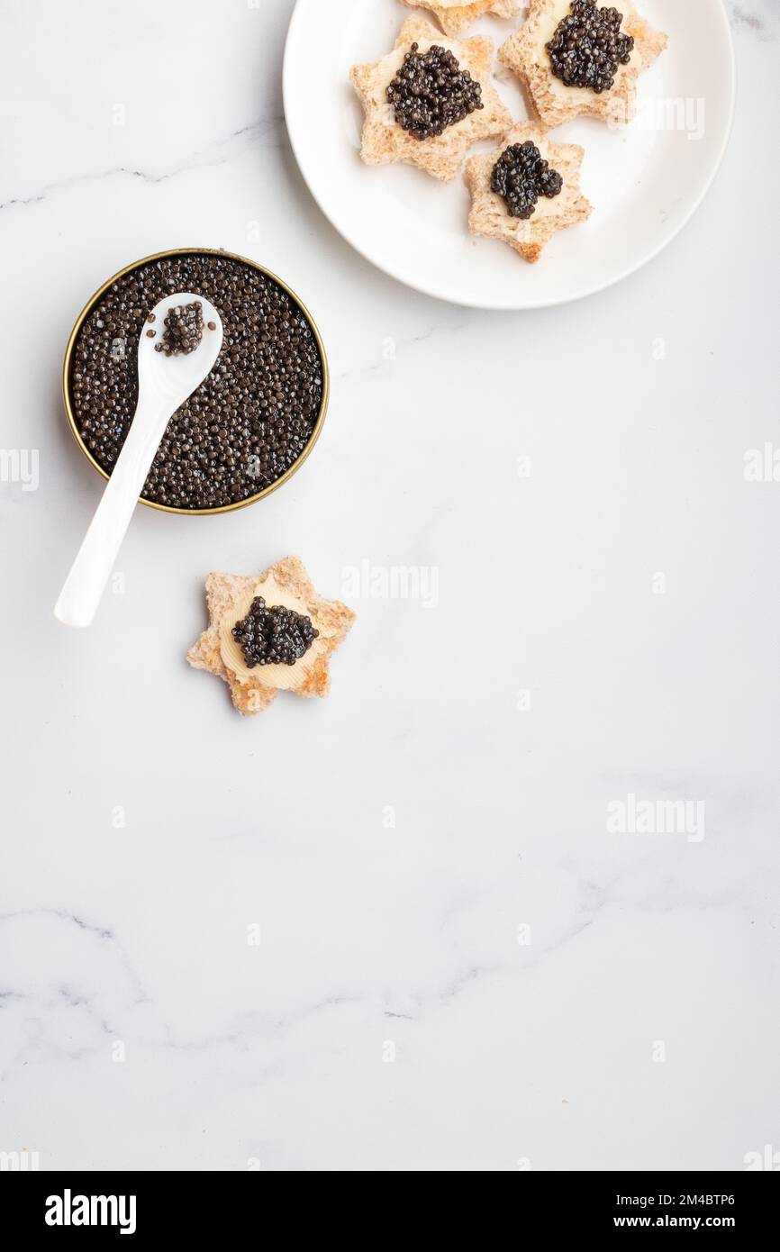 Antipasti neri al caviale stelle del pane con burro su sfondo bianco vista dall'alto verticale Foto Stock