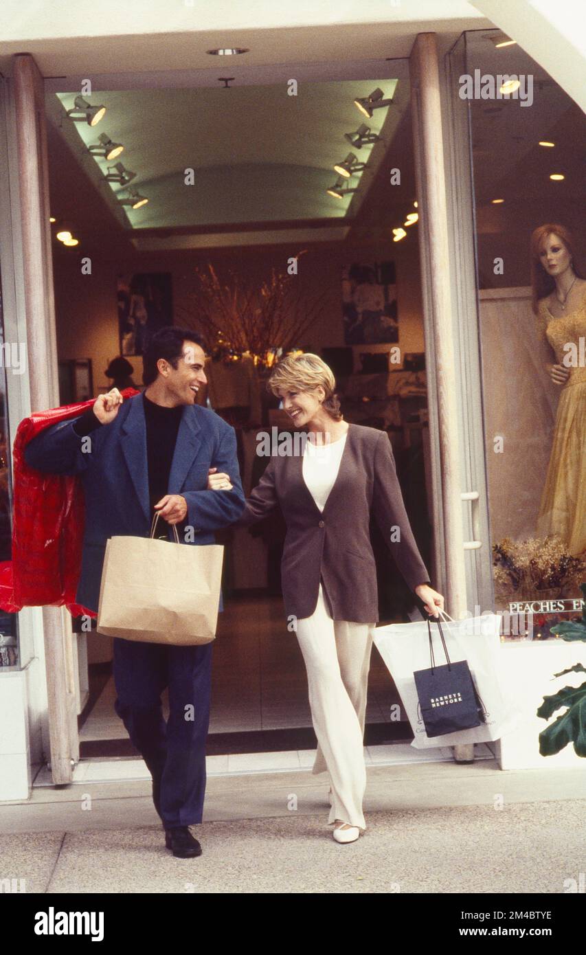 Coppia giovane e ben vestita che cammina con le borse dello shopping Foto Stock