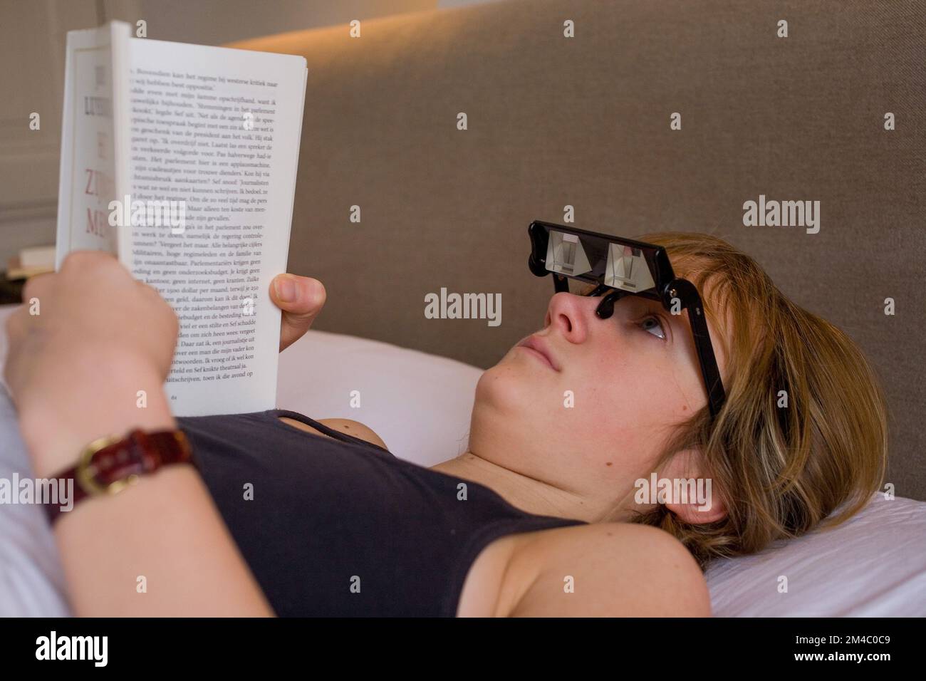 Con gli occhiali con angolo di visione di 90 gradi è possibile leggere un  libro a letto senza dolore al collo Foto stock - Alamy