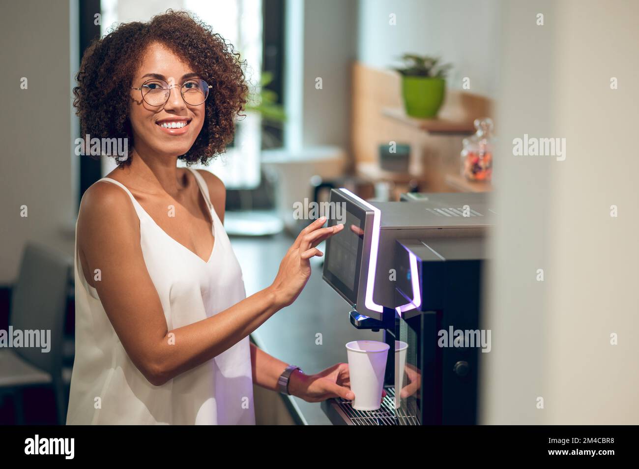 Dipendente dell'azienda che si fa un drink nella cucina dell'ufficio Foto Stock