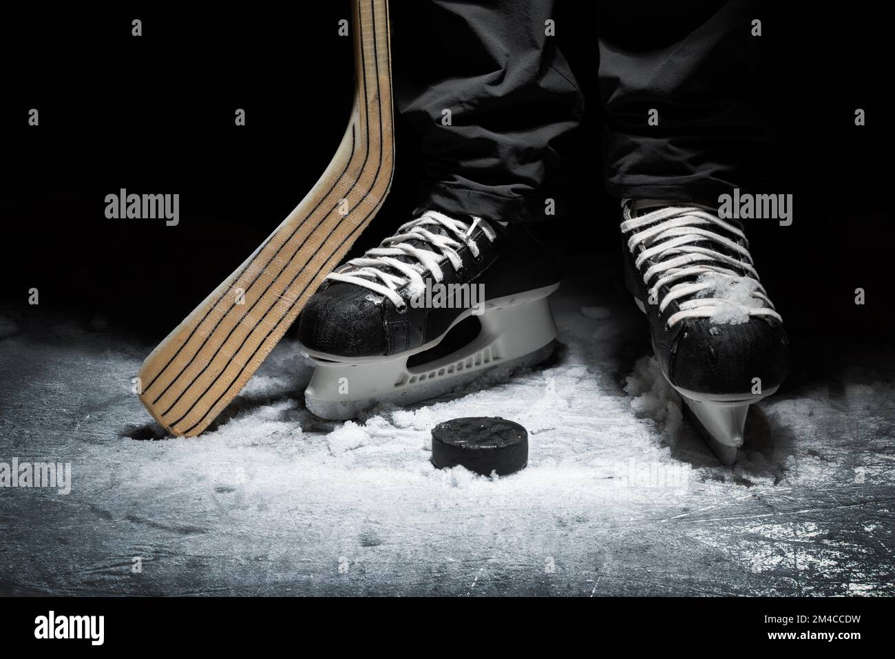 hockey su ghiaccio. primo piano dei pattini del giocatore con bastone e puck Foto Stock
