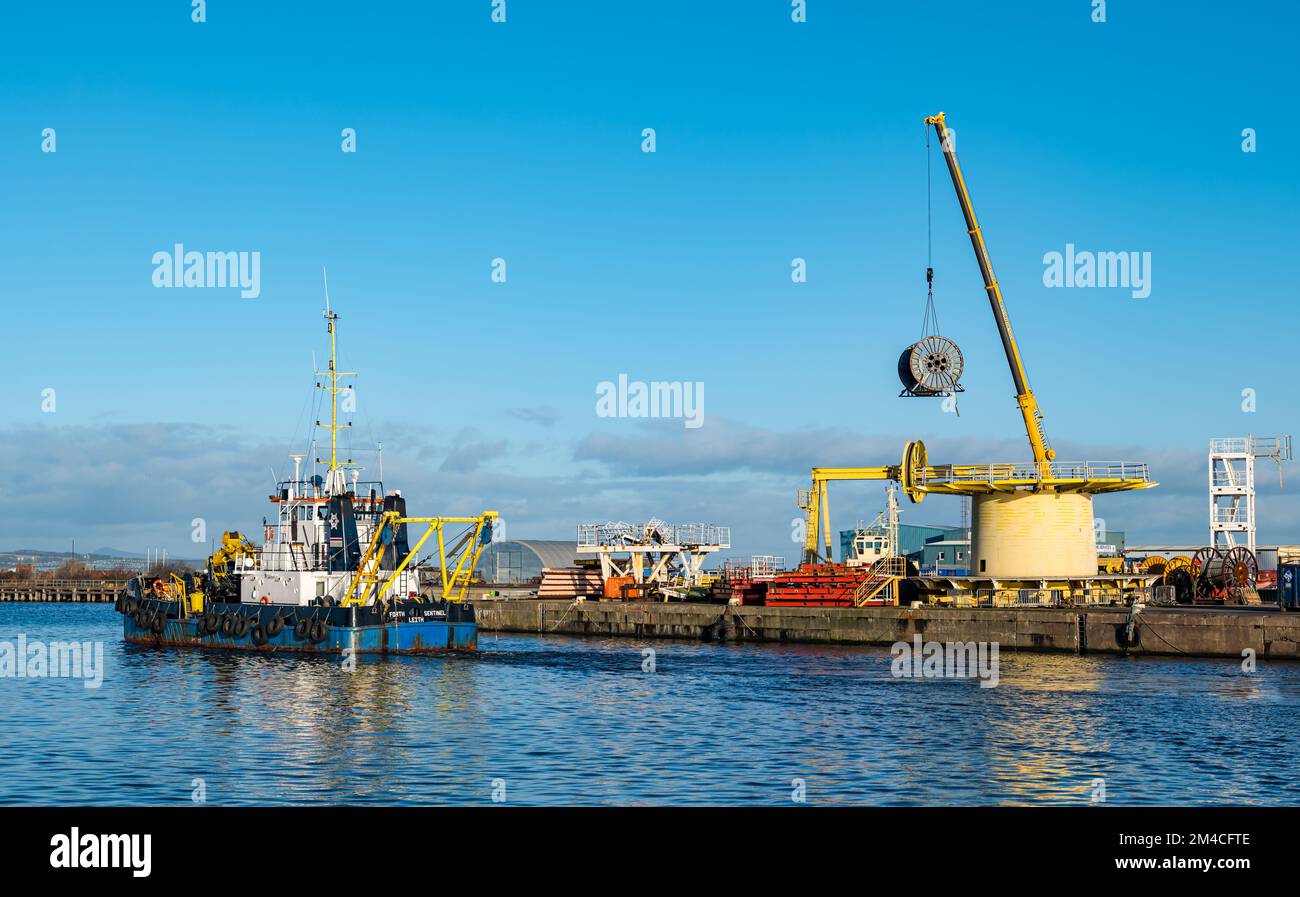 La nave di servizio Forth Sentinel che draga Leith Harbour con una ruota per cavi di sollevamento con gru sul molo, Edimburgo, Scozia, Regno Unito Foto Stock