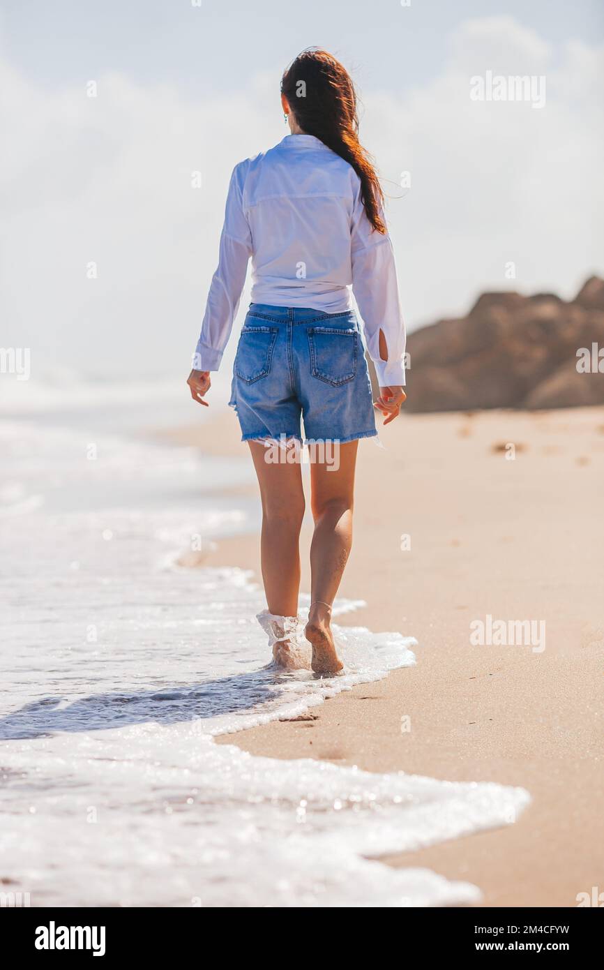 Giovane donna felice di camminare sulla spiaggia Foto Stock