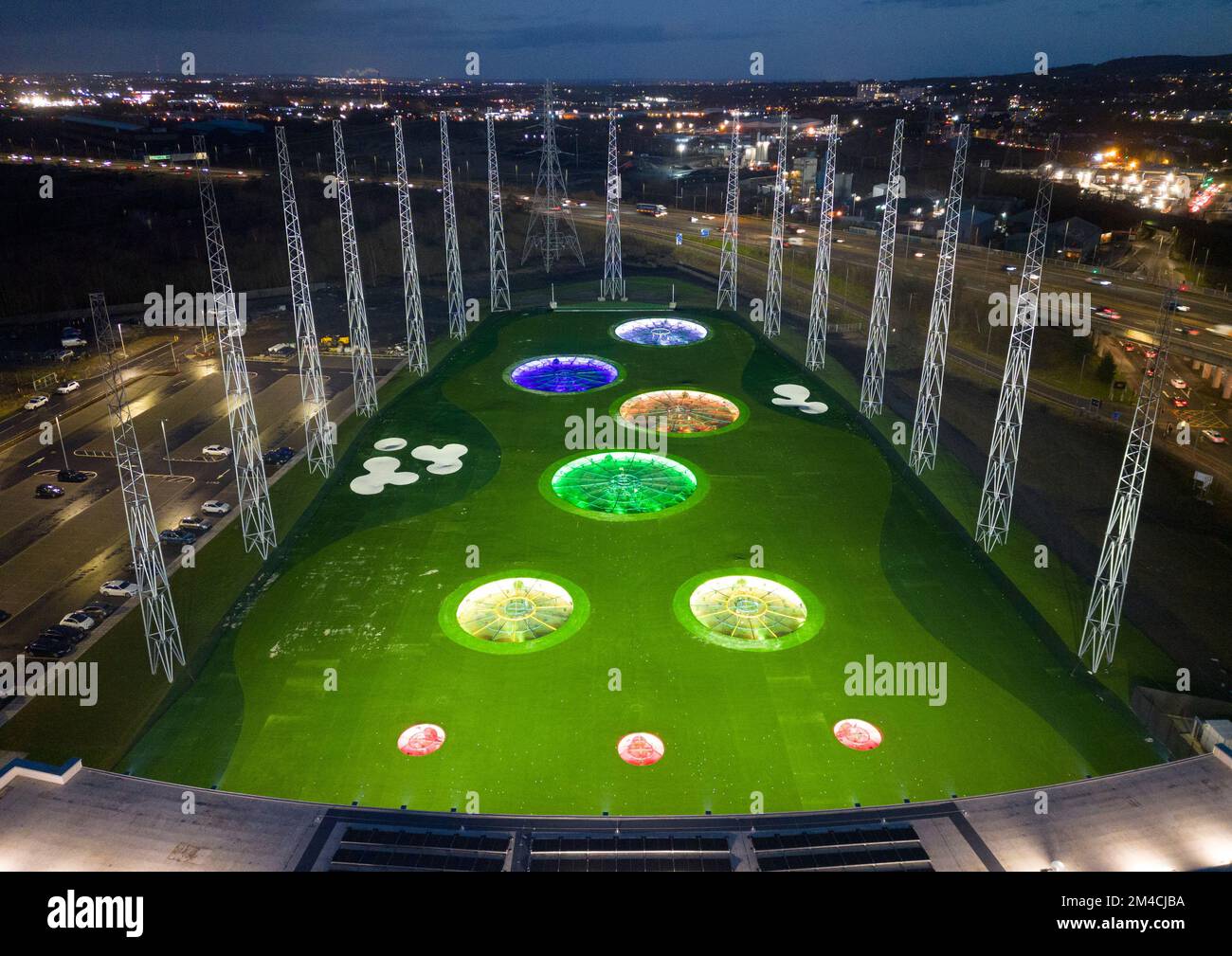 Glasgow, Scozia, Regno Unito. 20th dicembre 2022. Veduta aerea del nuovo driving range illuminato a Rutherglen, Glasgow. Il Topgolf Glasgow è stato inaugurato nel fine settimana ed è il primo luogo di divertimento per il golf in Scozia. La gamma dispone di 3 livelli e 70 baie elettroniche per tutte le stagioni, dove gli ospiti giocano a una varietà di giochi di golf target basati su computer. Iain Masterton/Alamy Live News Foto Stock