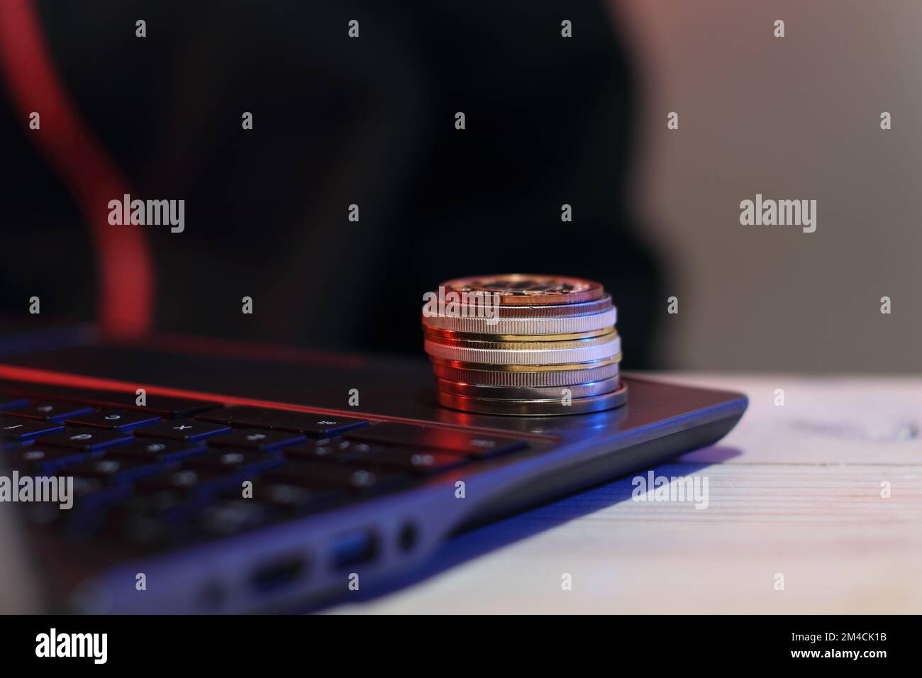 pila di monete nell'angolo di un computer portatile con una persona sullo sfondo Foto Stock pila di monete nell'angolo di un computer portatile con una persona sullo sfondo Foto Stock