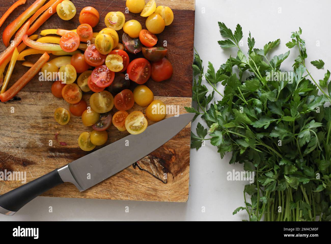 Taglieri da cucina con coltello, prezzemolo e pomodori Foto Stock