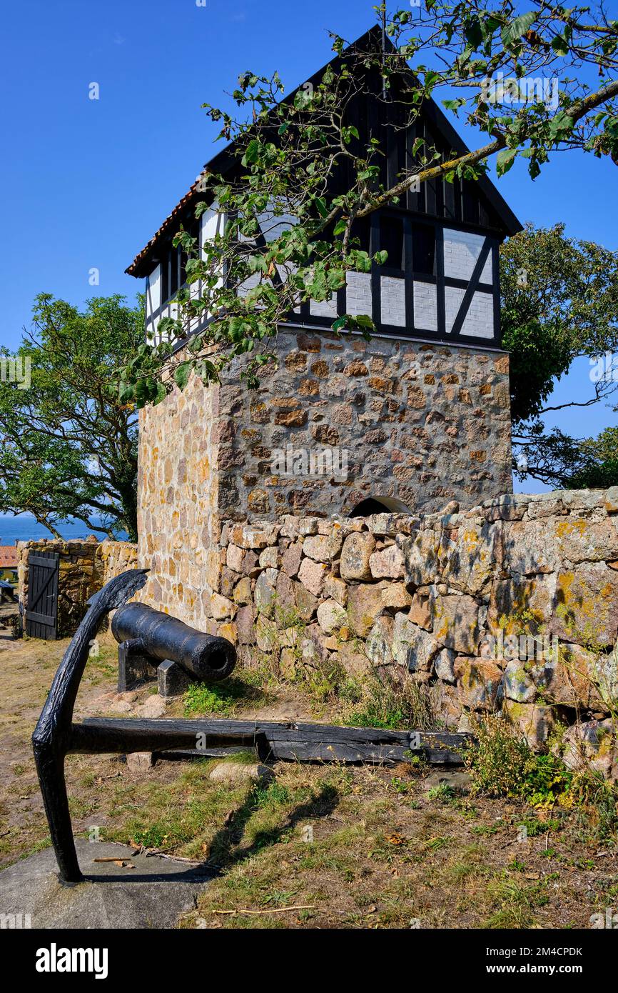 Fuori e fuori sulle isole Ertholmen, vecchio cannone e ancora di nave di fronte al campanile staccata della vecchia chiesa a Christiansö, Ertholmene, Danimarca. Foto Stock