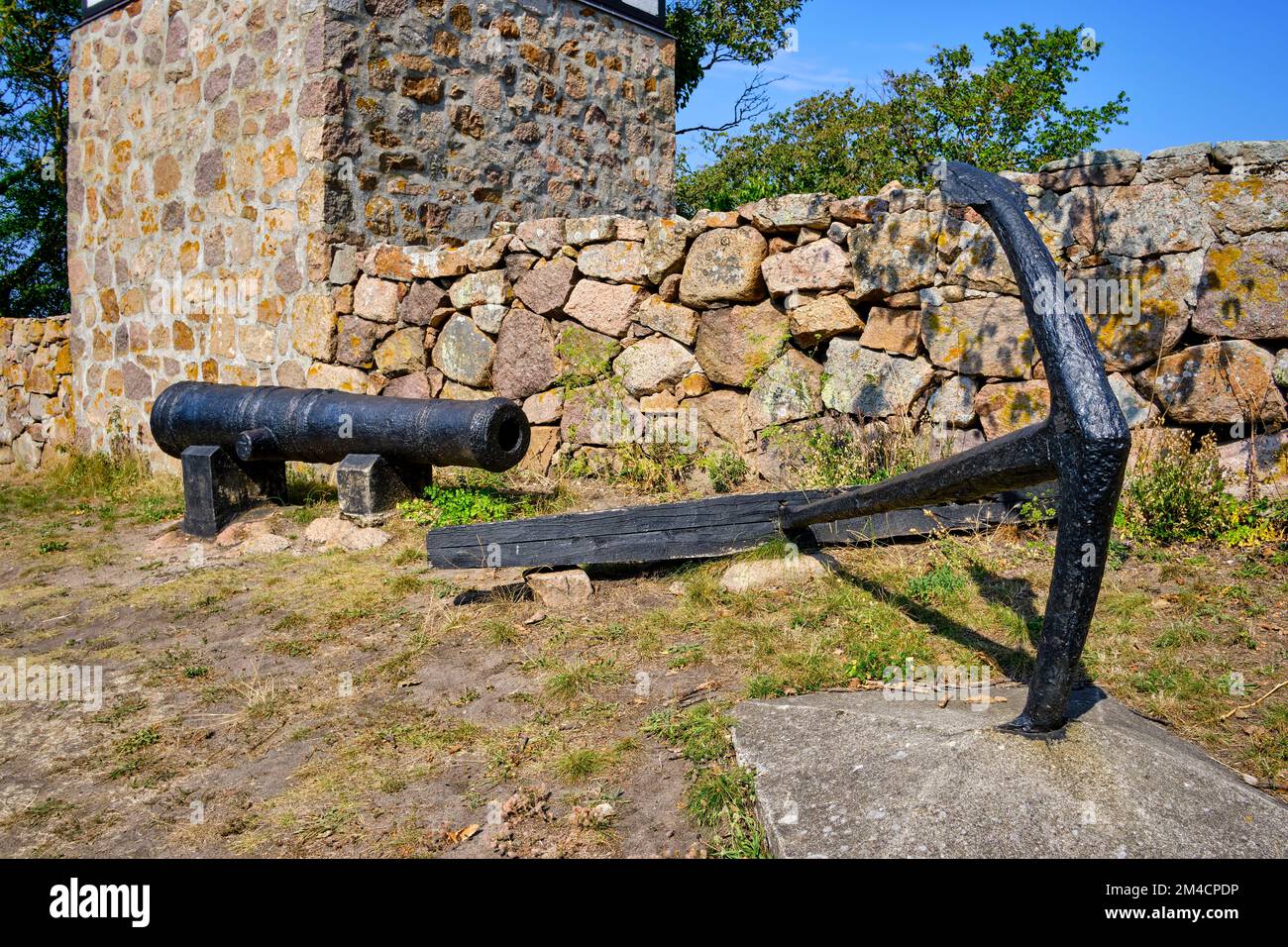 Fuori e fuori sulle isole Ertholmen, vecchio cannone e ancora di nave di fronte al campanile staccata della vecchia chiesa a Christiansö, Ertholmene, Danimarca. Foto Stock
