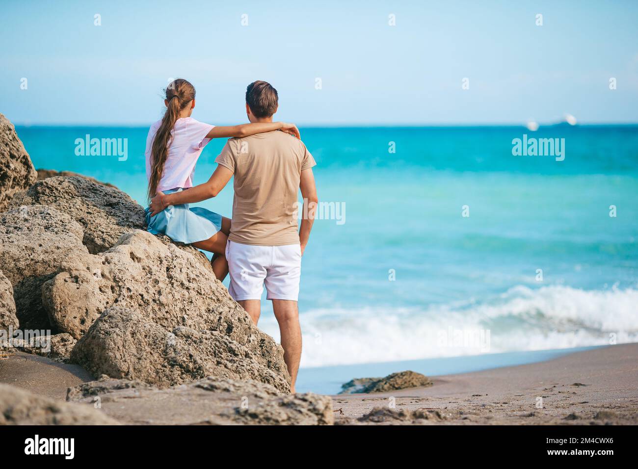La famiglia di un giovane padre e di una simpatica figlia godono della vista sul mare sulla spiaggia Foto Stock