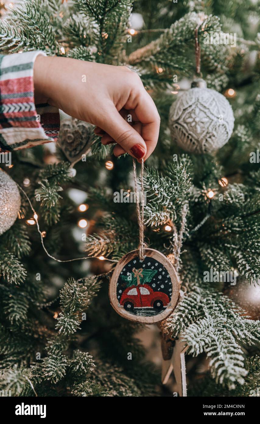 Foto ravvicinata della donna che decora l'albero di natale con ornamento dipinto a mano fai da te Foto Stock