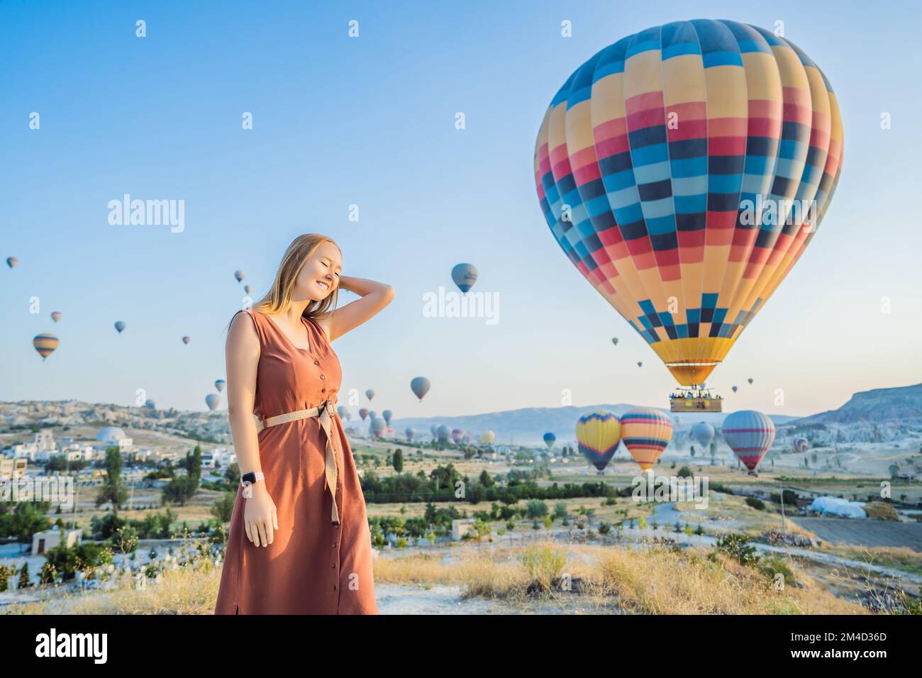 Donna turistica che guarda mongolfiere in Cappadocia, Turchia. Buon viaggio in Turchia concetto. Donna in cima a una montagna che gode di una vista meravigliosa Foto Stock