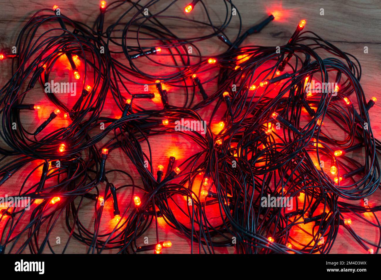 luci rosse di natale aggrovigliate su un tavolo di legno Foto Stock